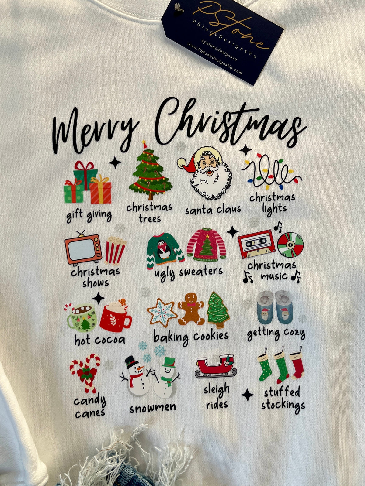 White sweatshirt with Merry Christmas and various holiday graphics: gift giving, christmas trees, santa claus, christmas lights, chrismas snow, ugly sweaters, christmas music, hot cocoa, baking cookies, getting cozy, candy canes, snowmen, sleigh rides, and stuffed stockings