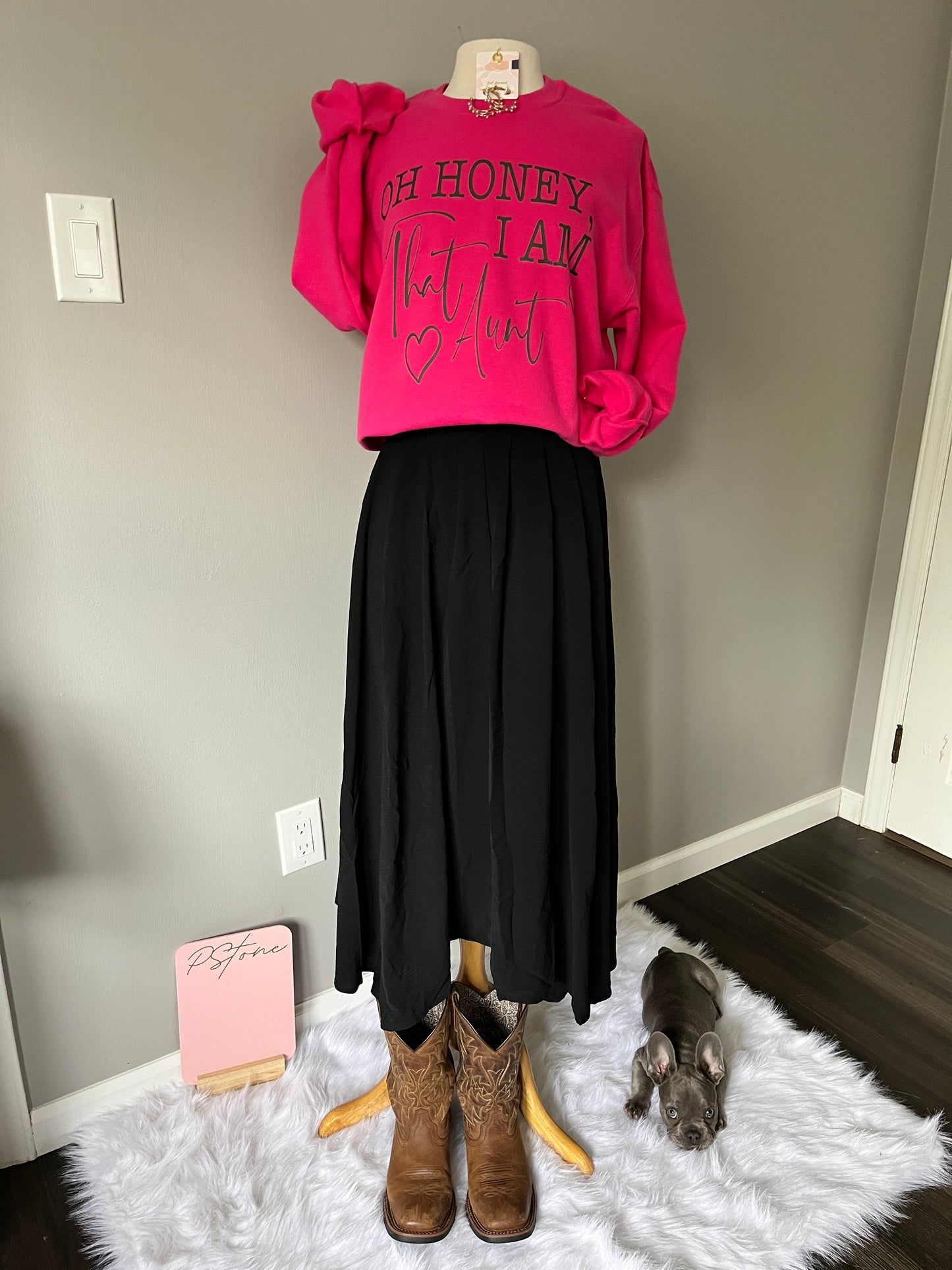 PStone mascot, Gus in the bottom right corner, picks his favorite look: Oh Honey I Am That Aunt pink sweatshirt, paired with the Wendy Skirt in black, and finished with cowboy boots.