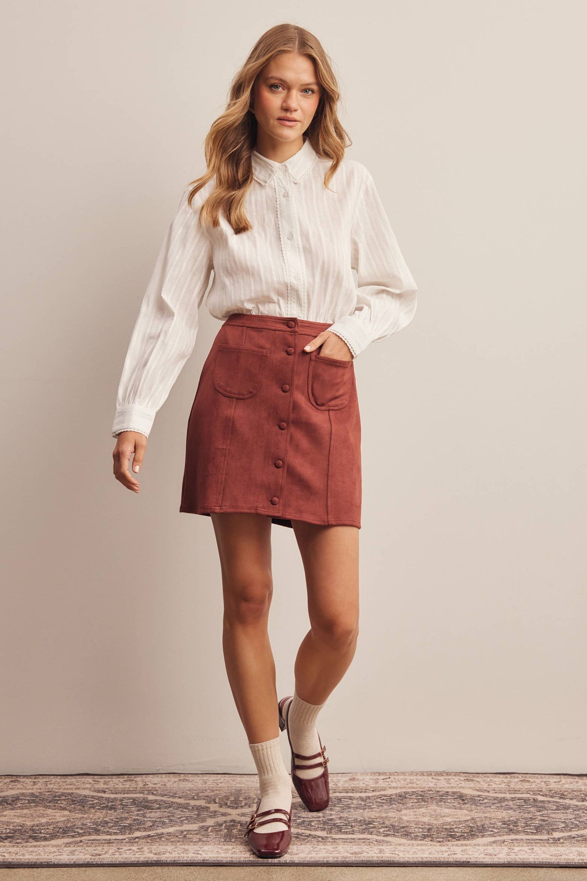 Woman wearing a white blouse and red skirt against a plain background