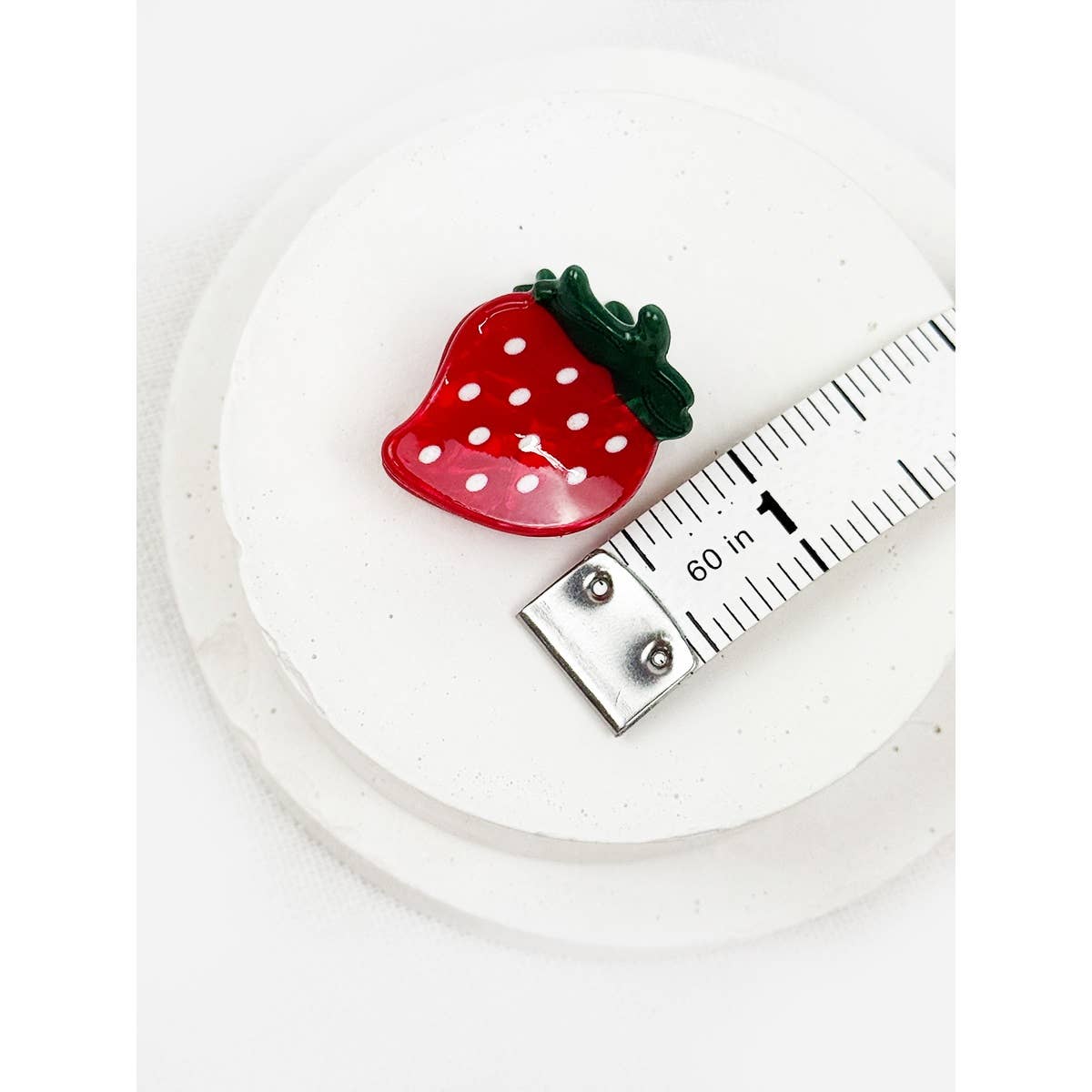 Strawberry-shaped object next to a ruler on a white background