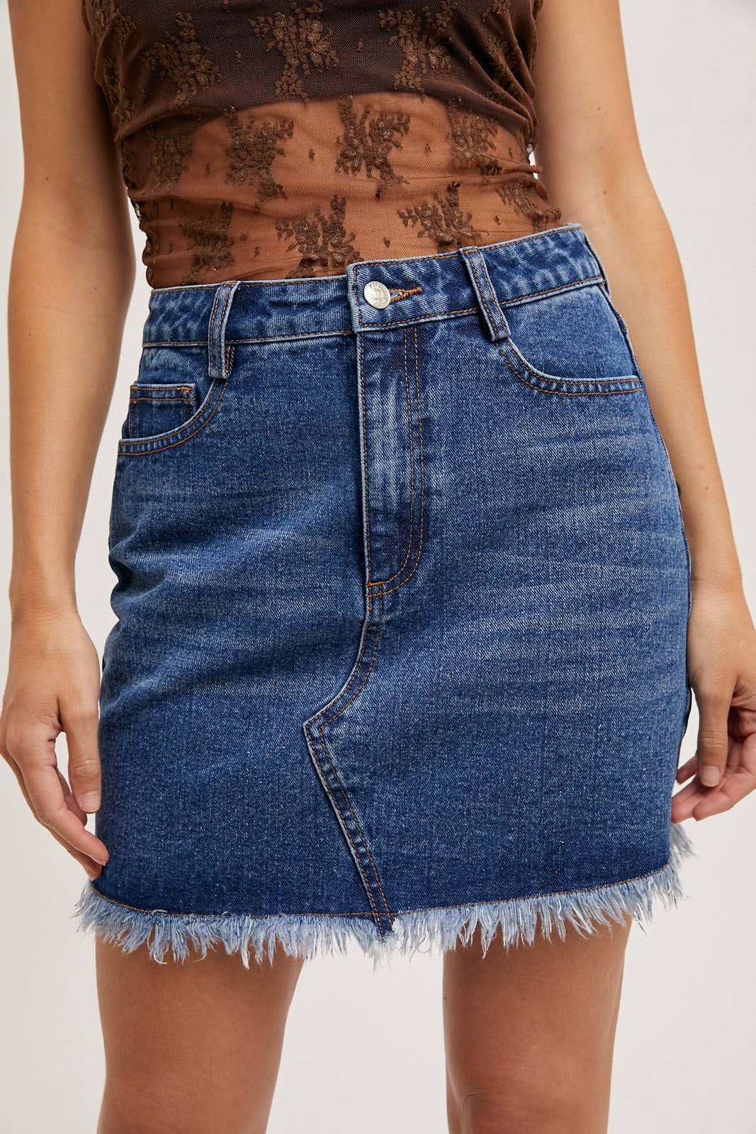 Person wearing a blue denim skirt on a plain background