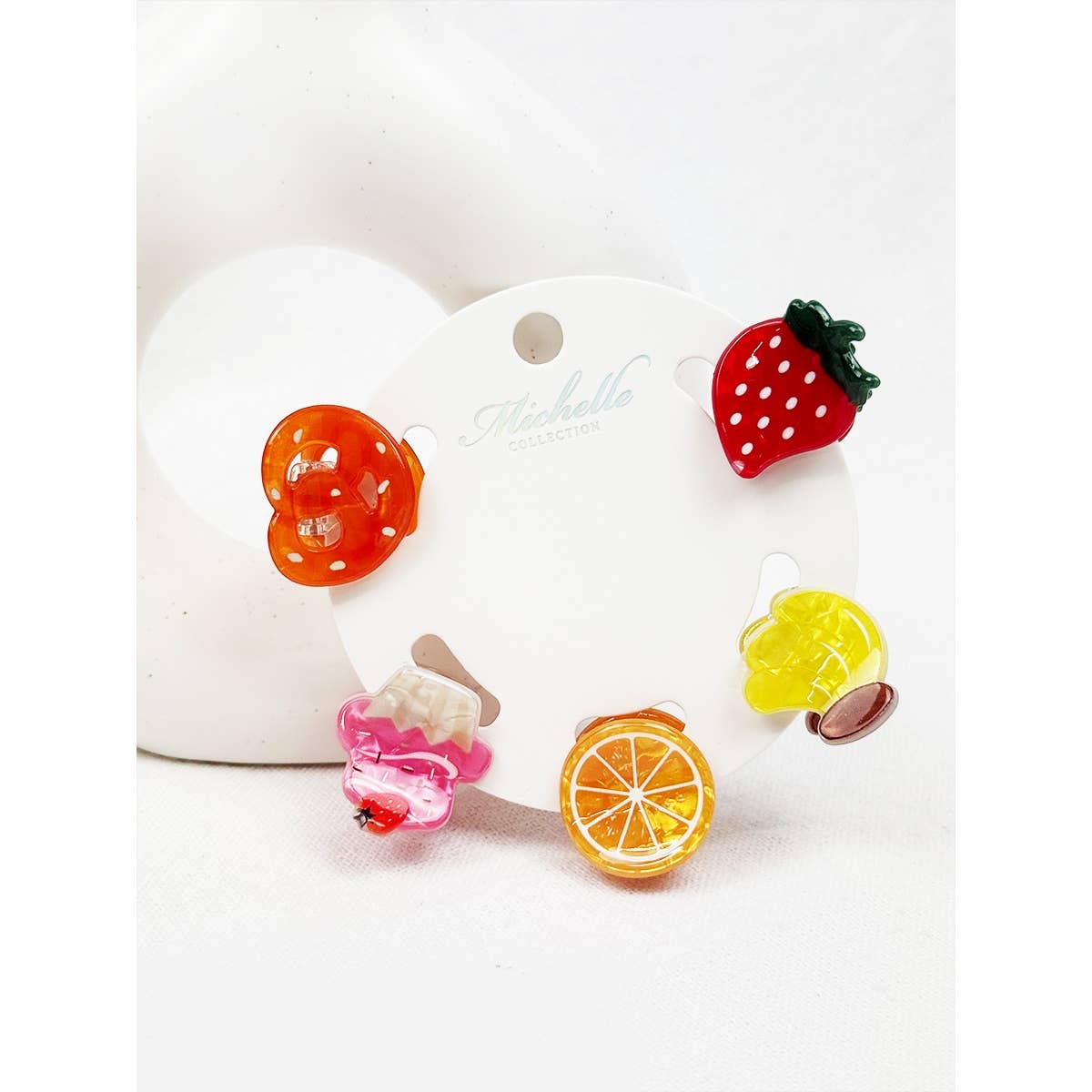 Fruit-themed hair clips on a round card with a white background