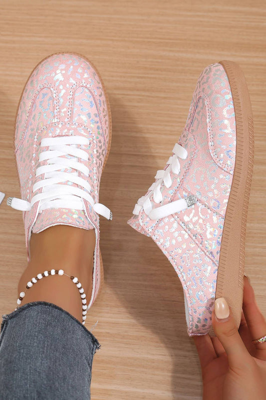 Woman trying on pink glittery leopard sneakers with white laces on a wooden floor.