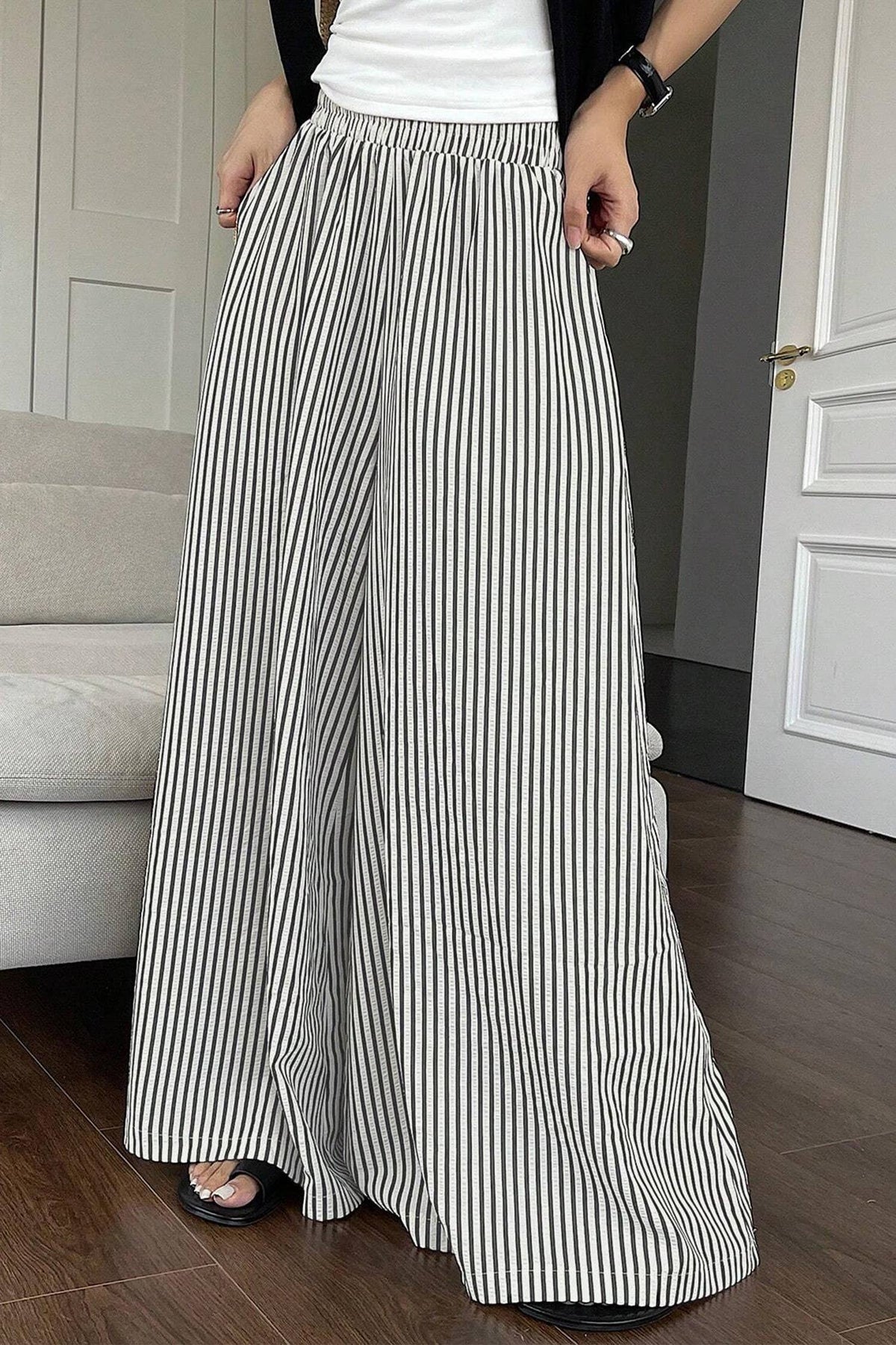 Person wearing black and white striped wide-leg pants indoors.