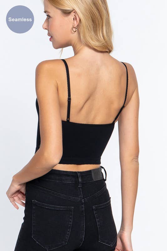 woman wearing a black cami and dark jeans from behind on a white background