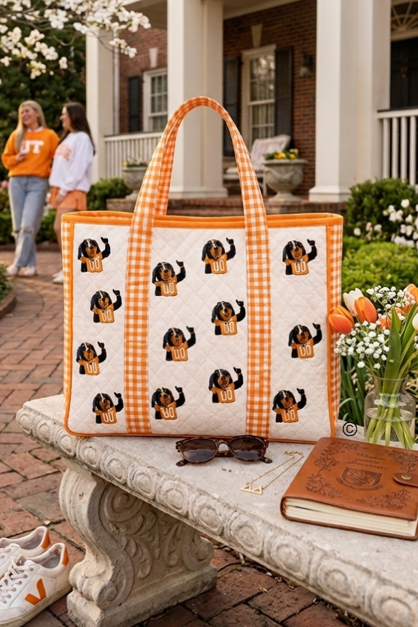 Tote bag with black and orange Smokey design on a stone bench outdoors