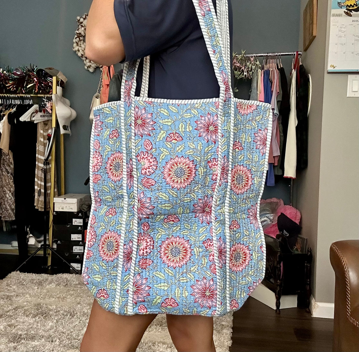 Person holding a floral-patterned bag in a clothing store.