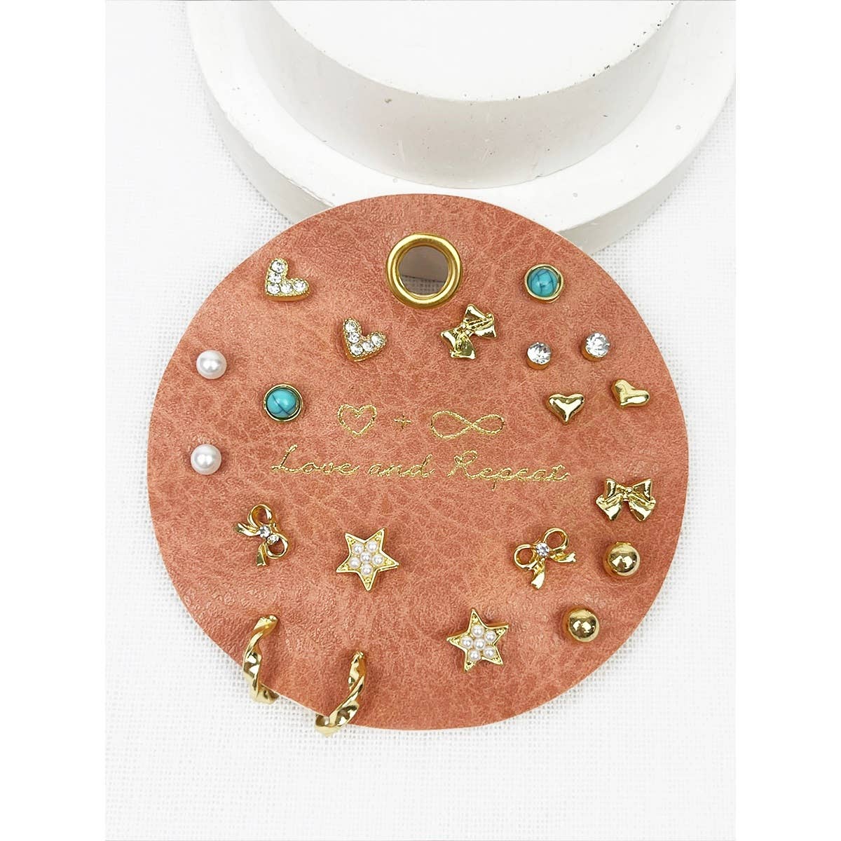 Round card with various small earrings on a white background