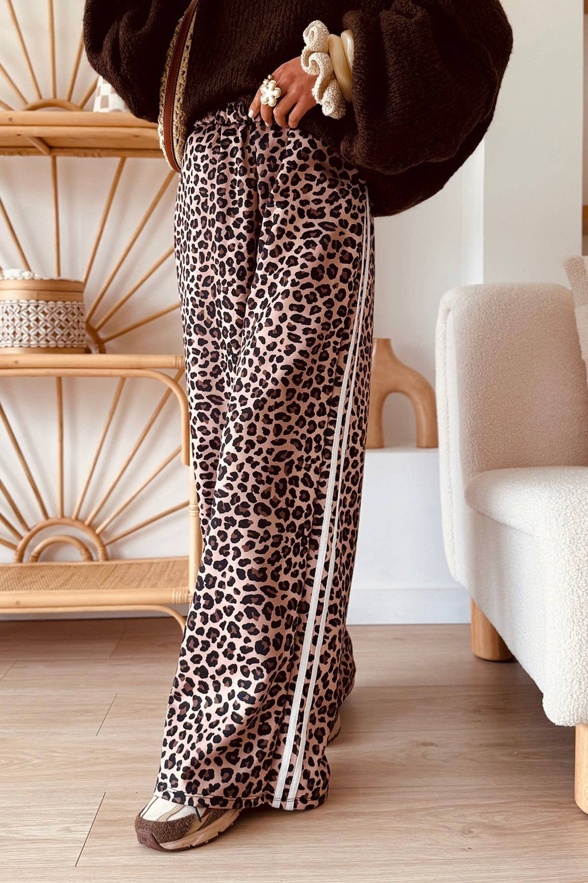 Person wearing leopard print pants with a white stripe indoors.