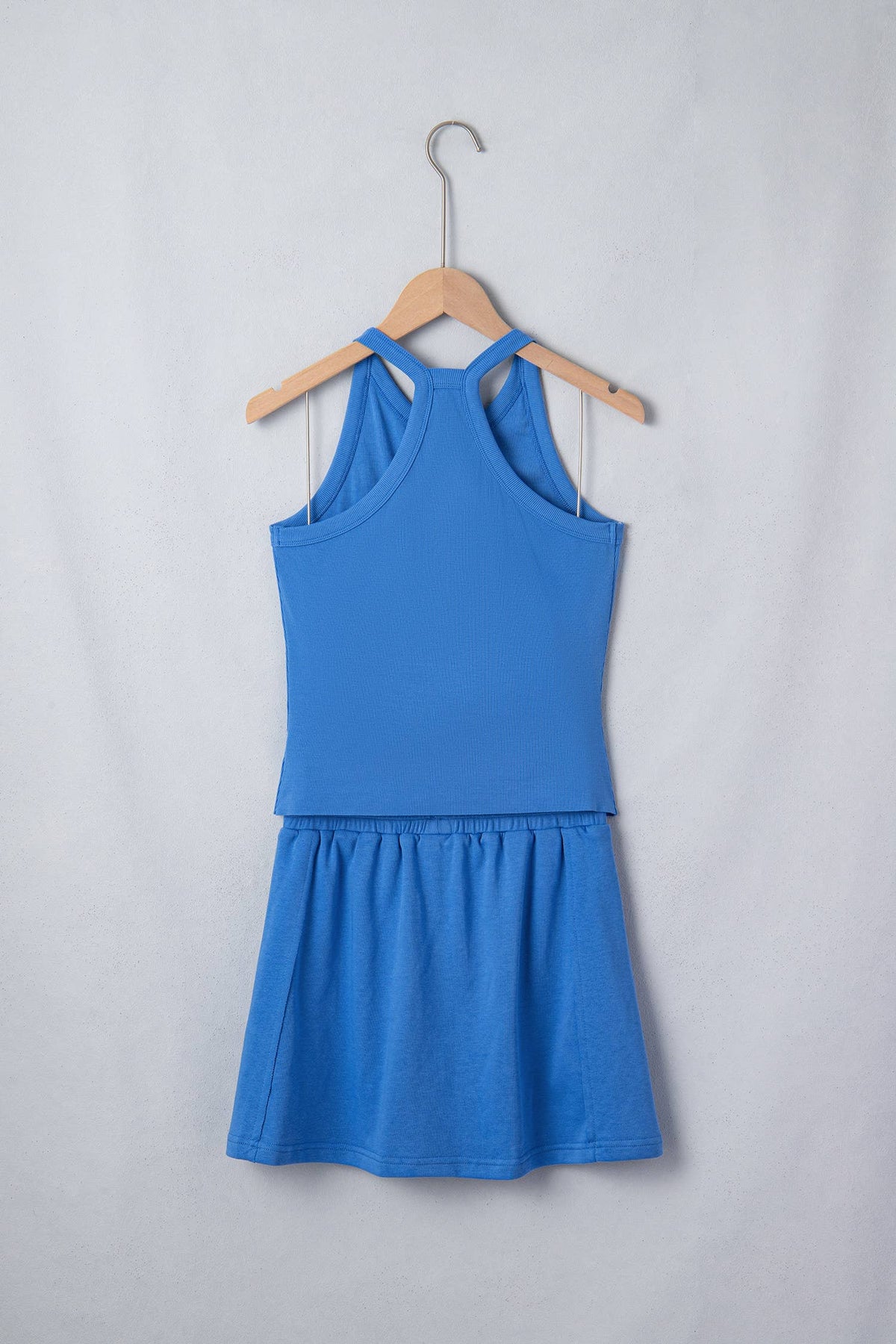 Blue tank and skort set on a hanger against a light gray background, back view.