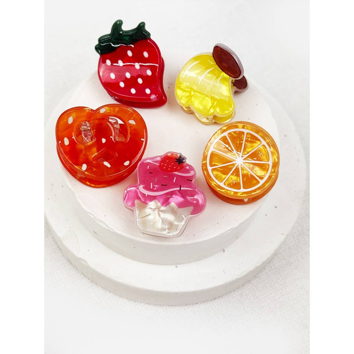 Set of colorful fruit-shaped hair clips on a white background