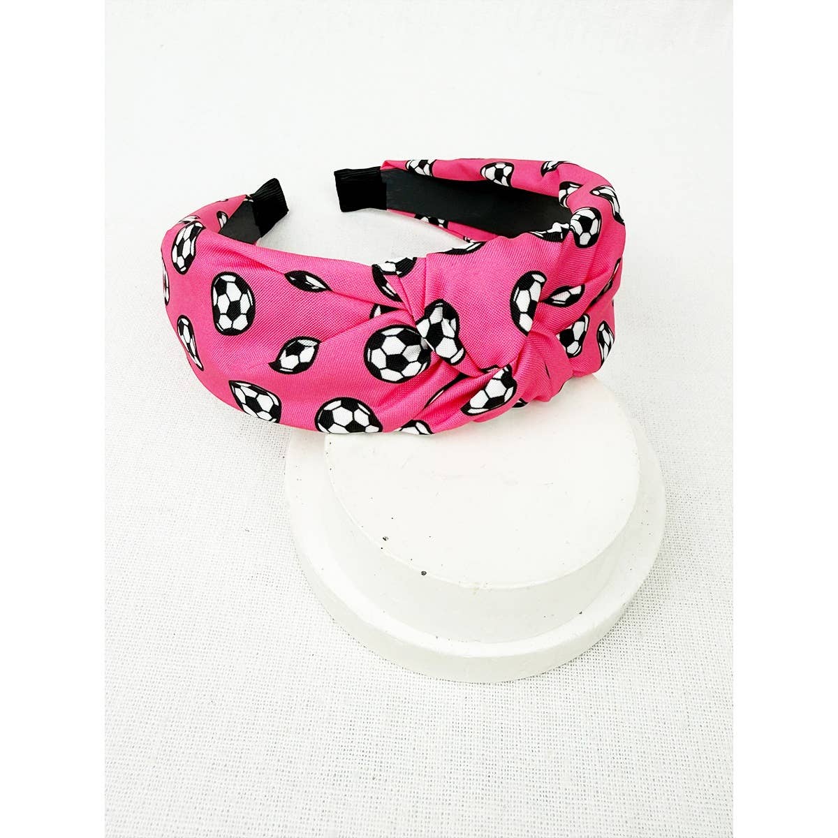 Pink headband with black and white soccer ball print on a white background