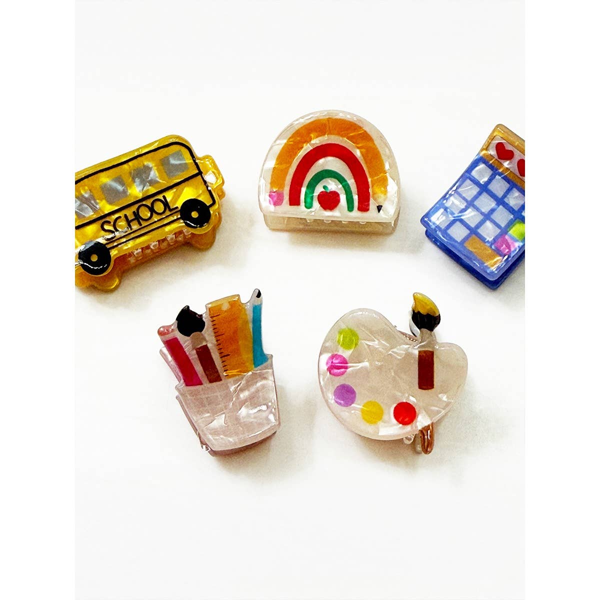Set of colorful school-themed hair clips on a white background