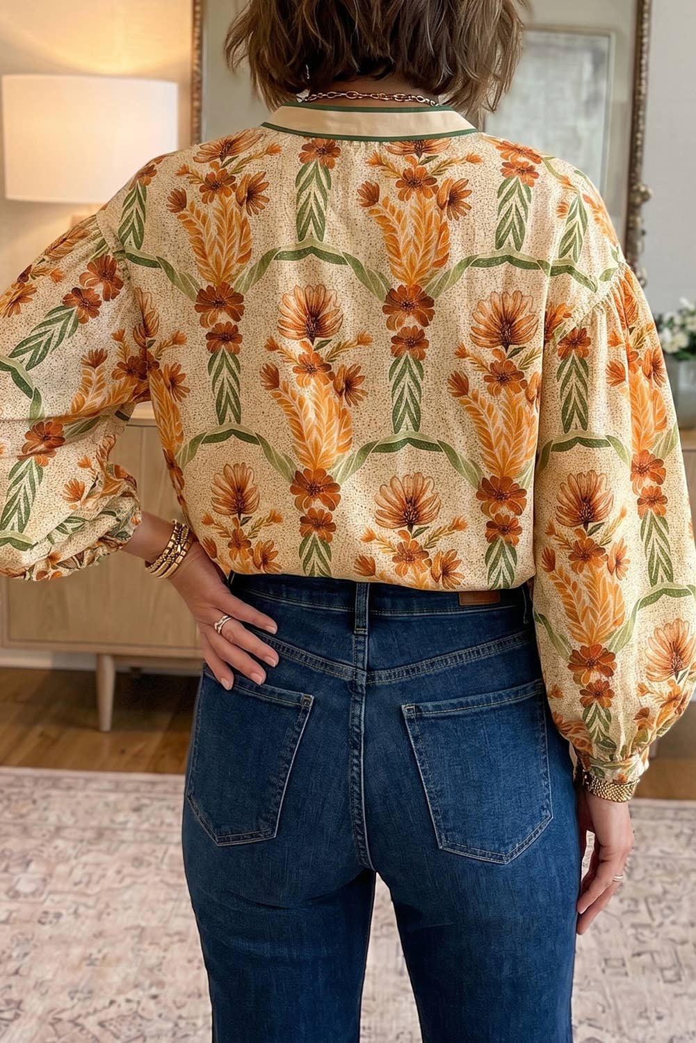 Person wearing a patterned blouse and jeans indoors