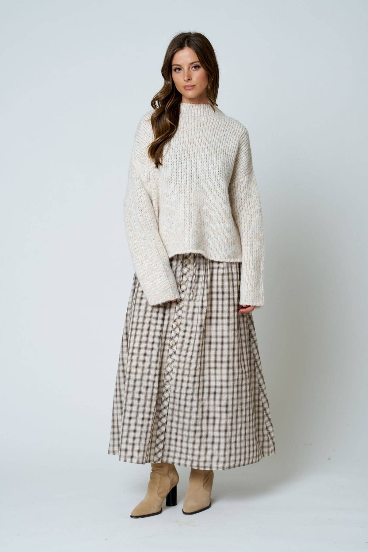 Woman wearing a white sweater and plaid skirt on a white background