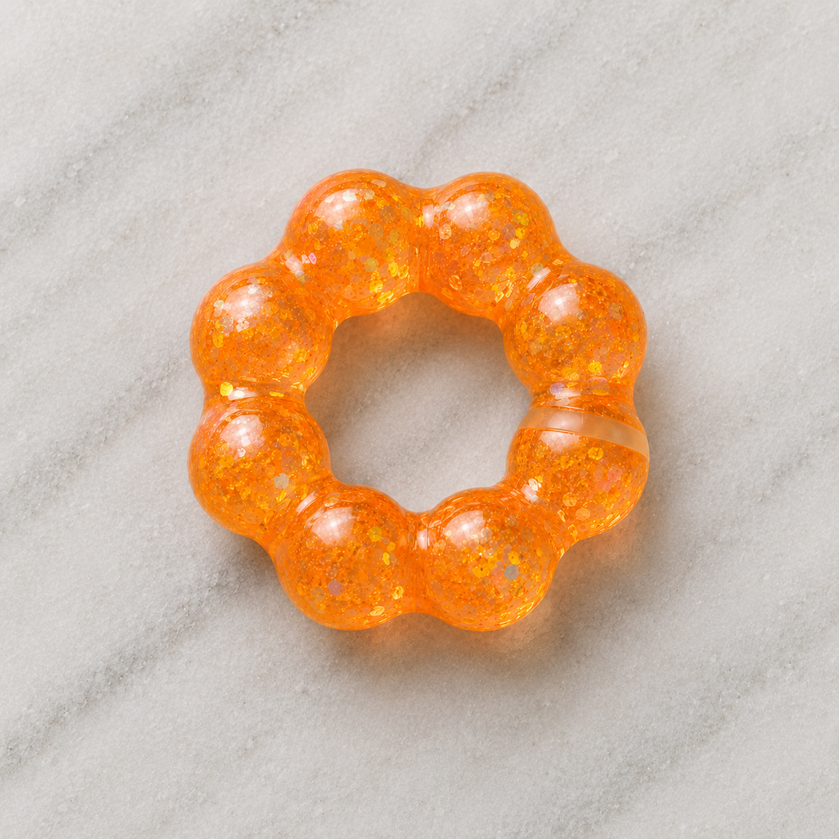 Orange squishy bracelet on a gray marble surface