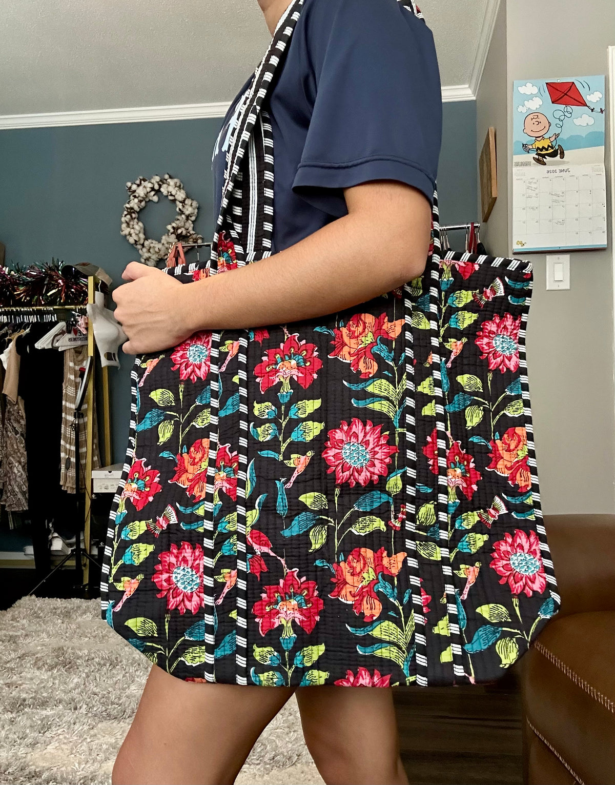 Person holding a floral tote bag in a store setting