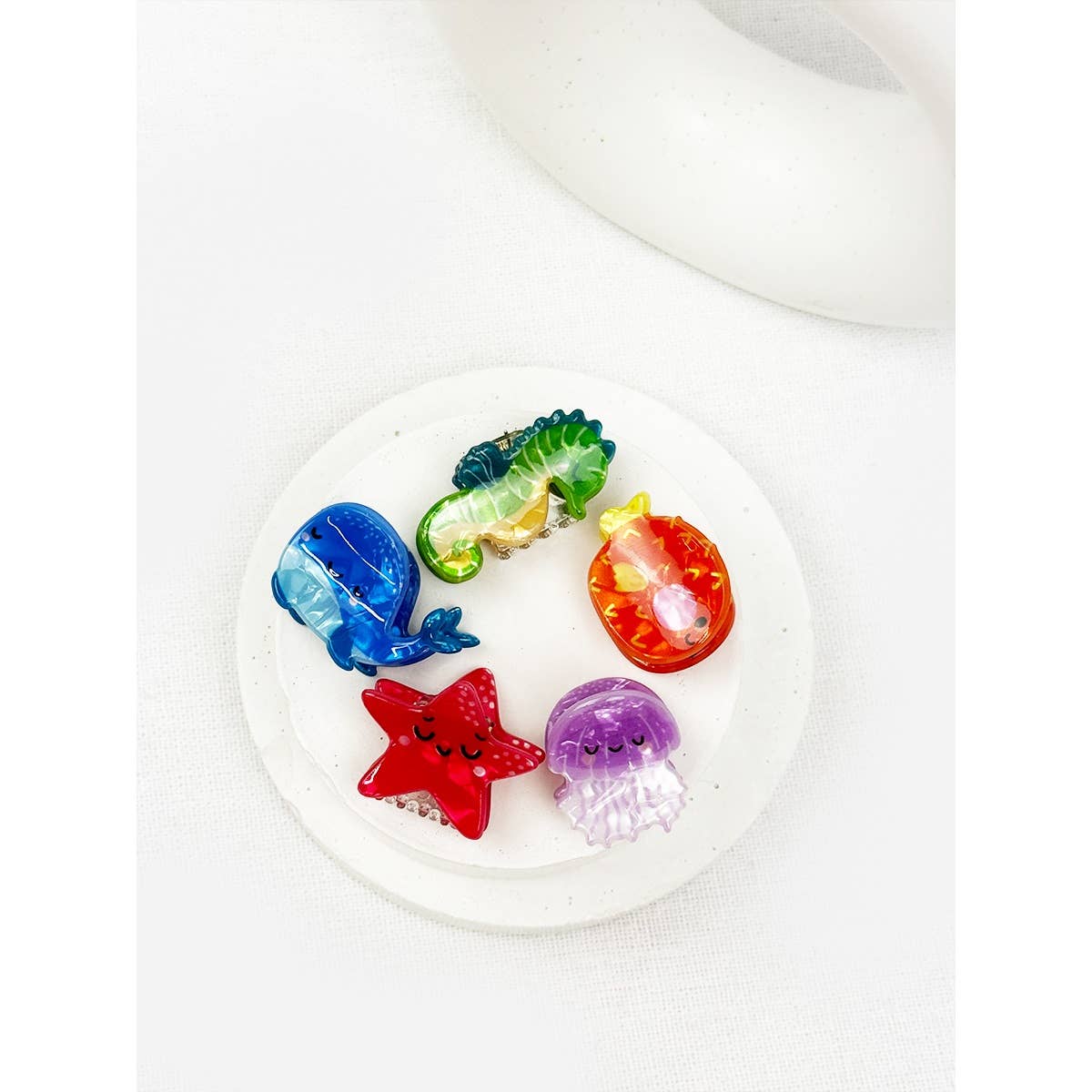 Colorful sea animal hair cliips like fish, starfish, and jellyfish on a white plate