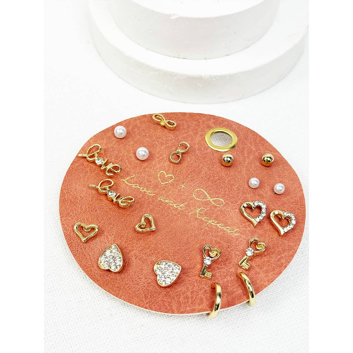 Set of gold and pearl earrings on a round coral card with text