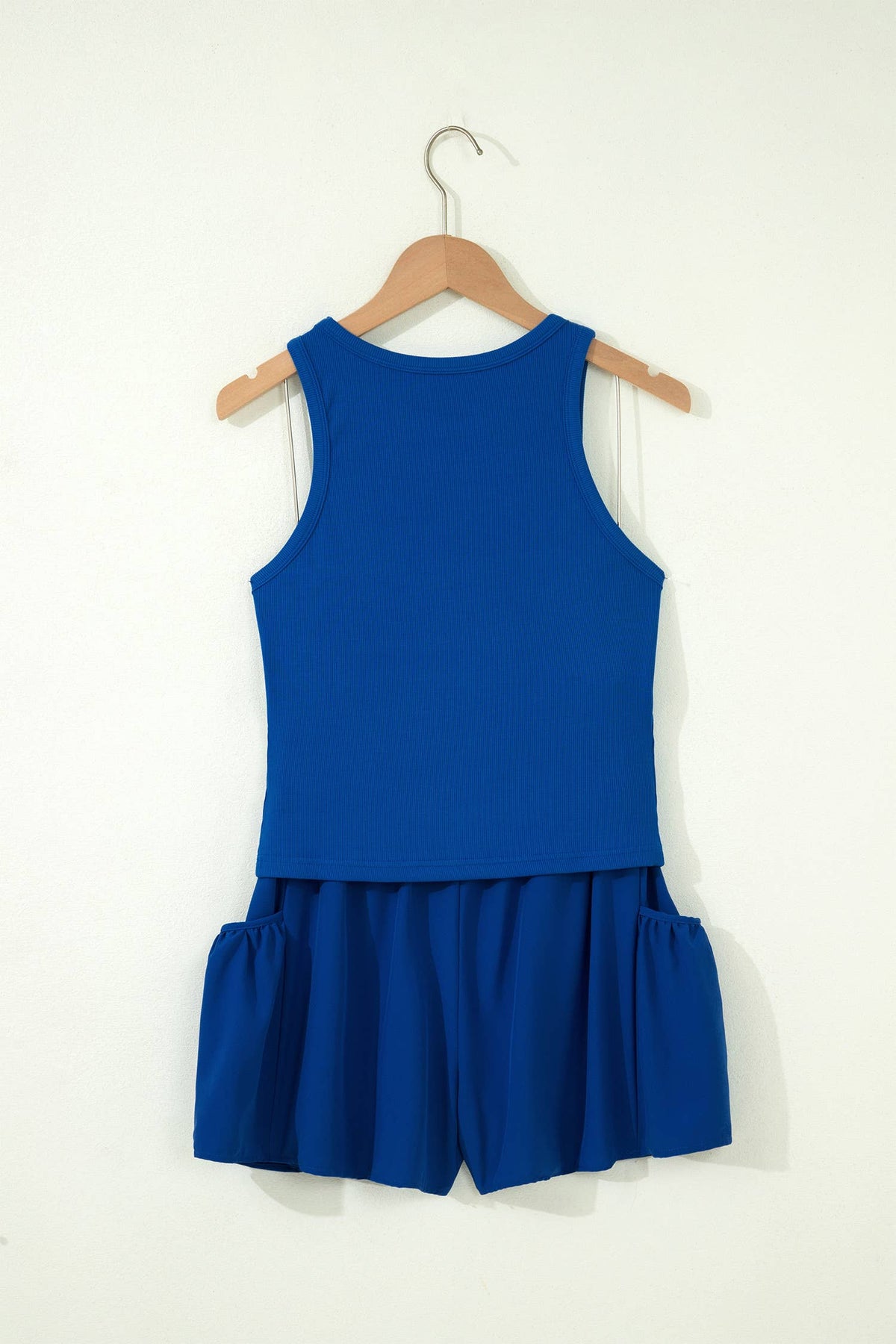 Blue sleeveless top with ruffled shorts on a hanger against a white background