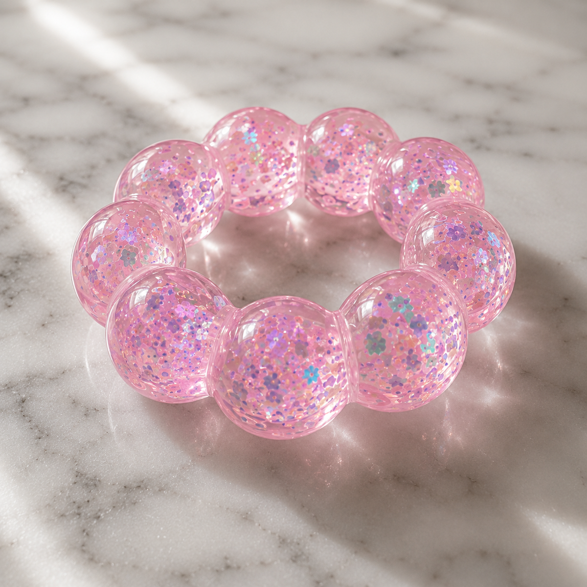 Pink glittery squishy bracelet on a marble surface