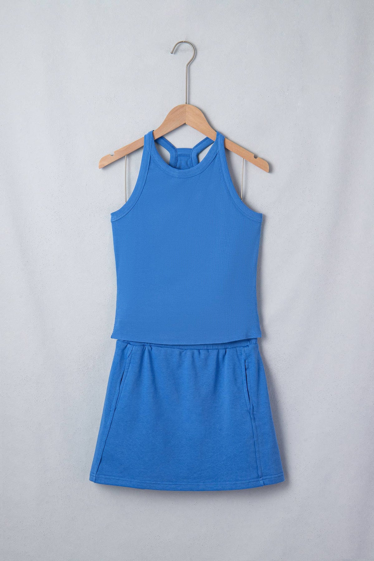 Blue tank and skort set on a hanger against a light gray background, front view.