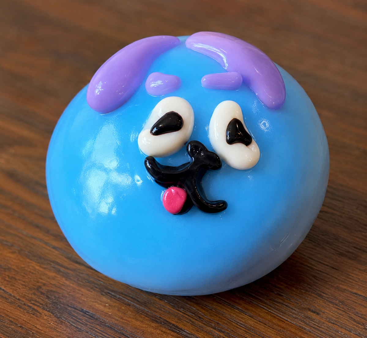 Blue squish ball with a cartoon face on a wooden surface