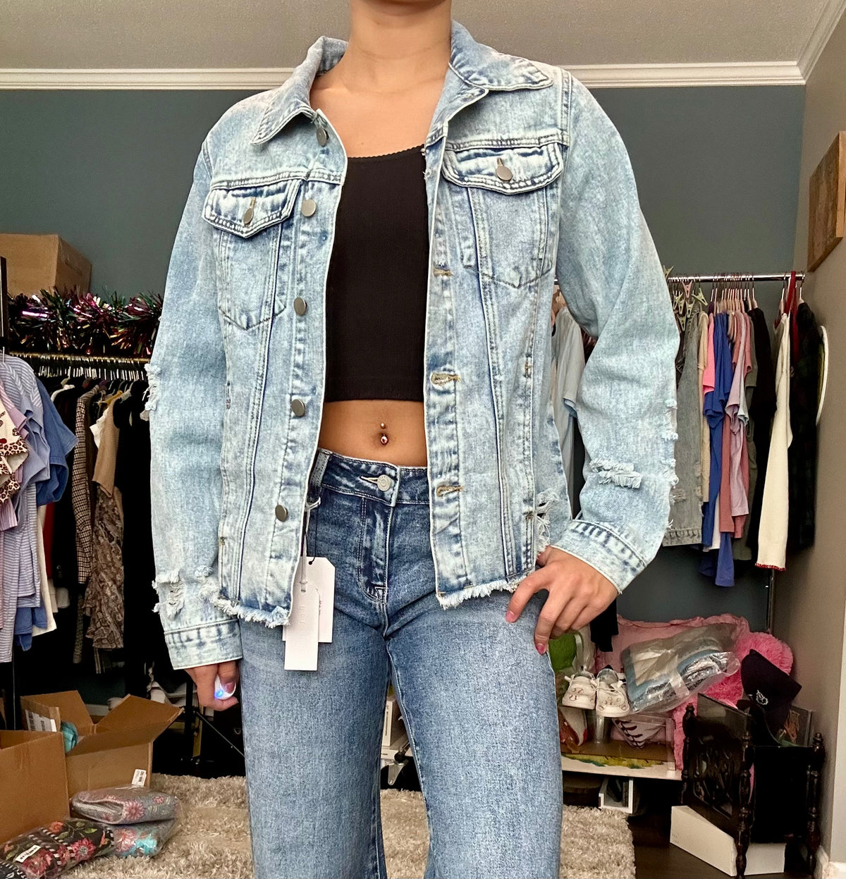 Person wearing a light blue denim jacket and jeans in a clothing store.