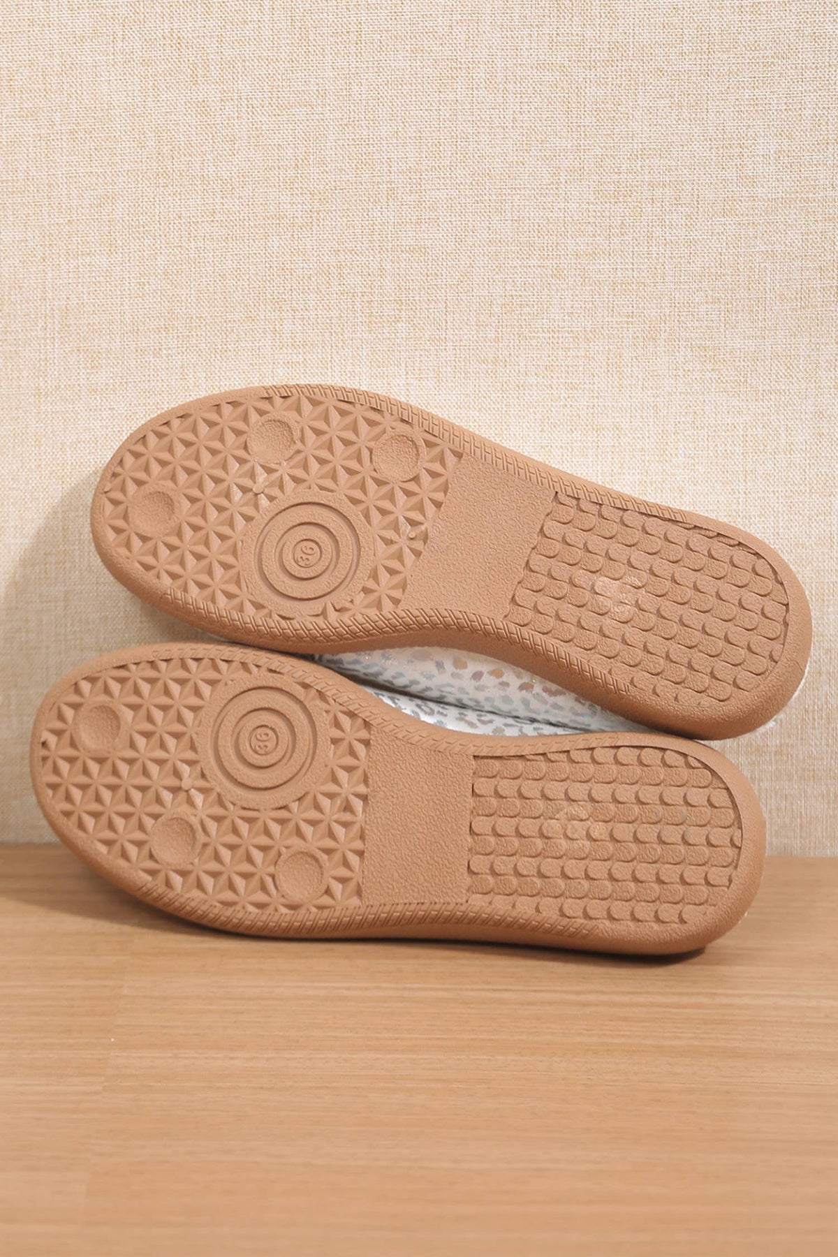 Close-up of brown shoe soles on a wooden surface with a beige textured background