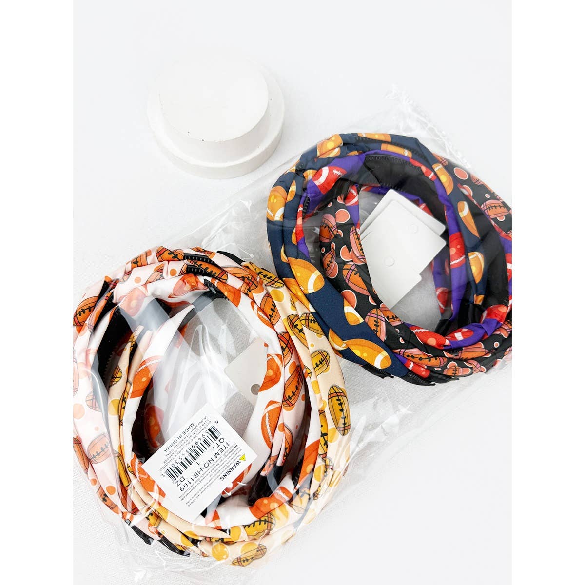 Football patterned headbands on a white surface with a visible brand label.