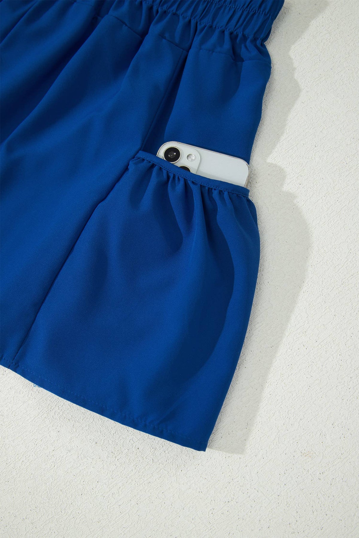 Blue shorts with a white object inside a pocket on a textured white background