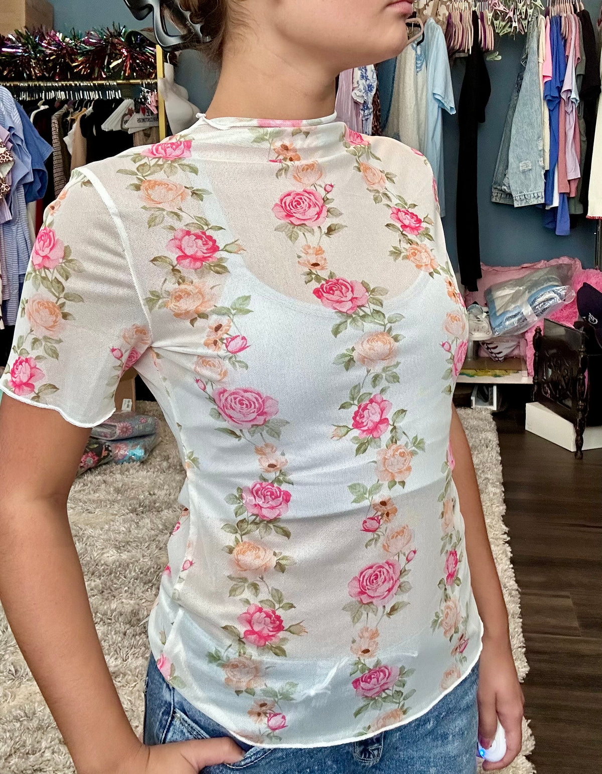 Person wearing a floral top in a clothing store setting