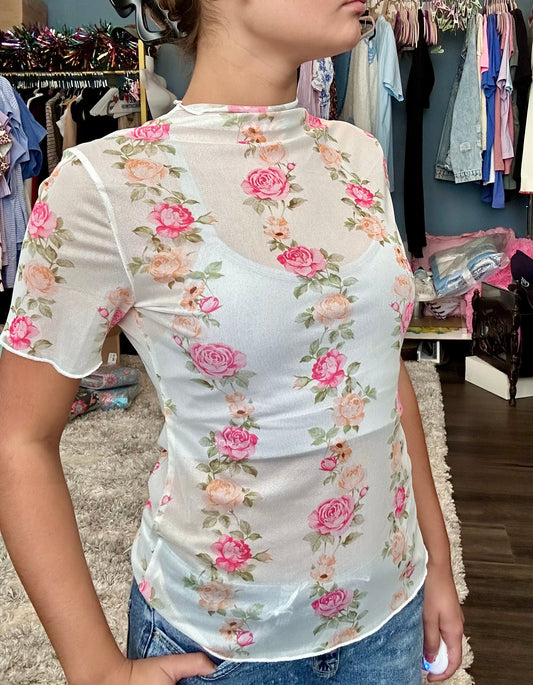 Person wearing a floral top in a clothing store setting