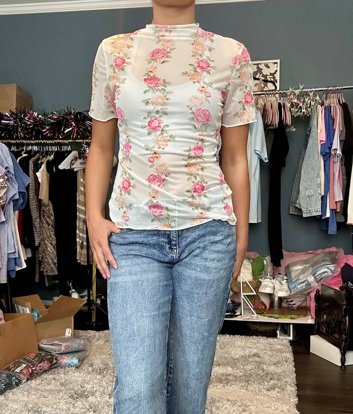 Person wearing a floral top and jeans in a clothing store.