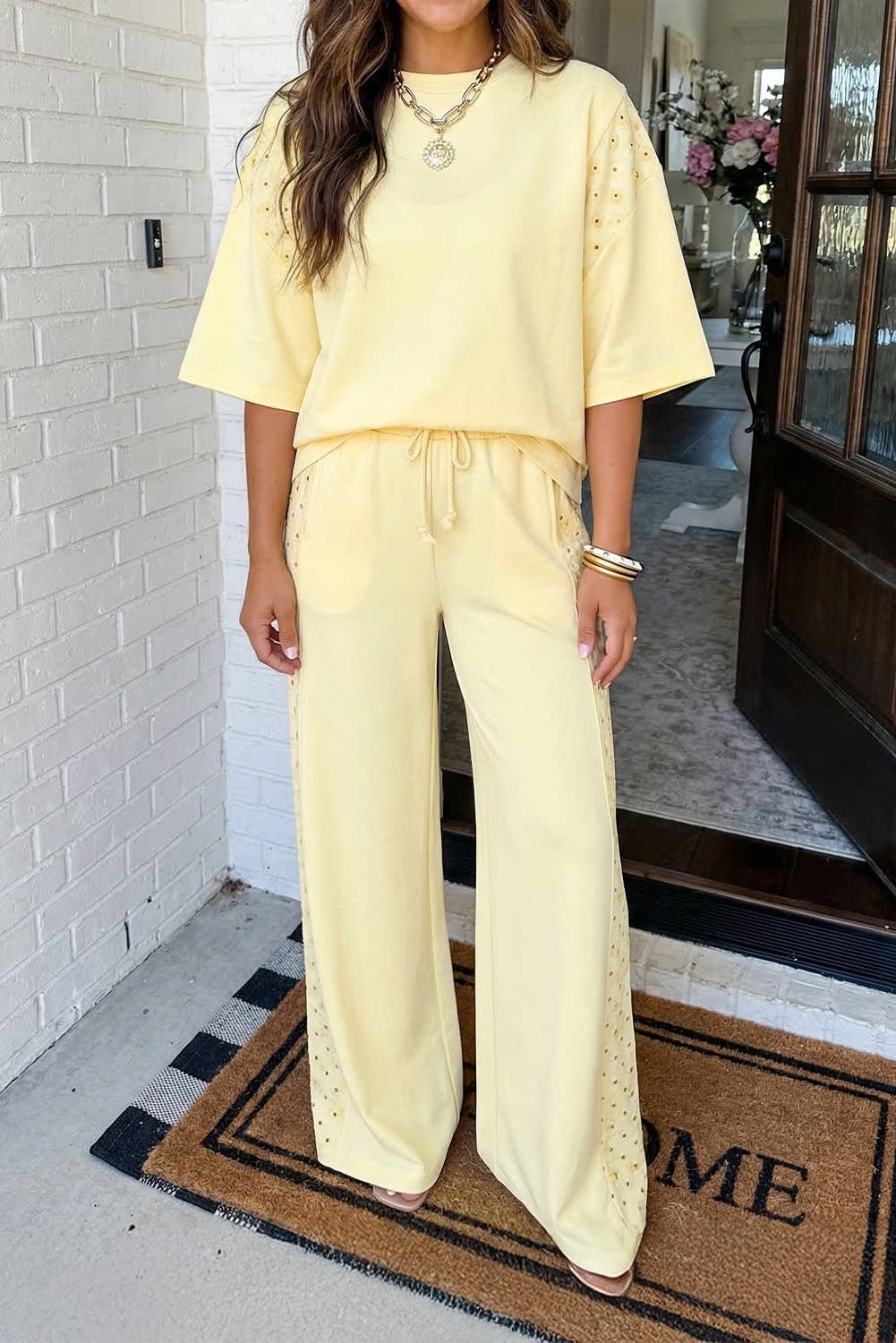 Woman in a yellow outfit standing on a doormat with 'HOME' text.