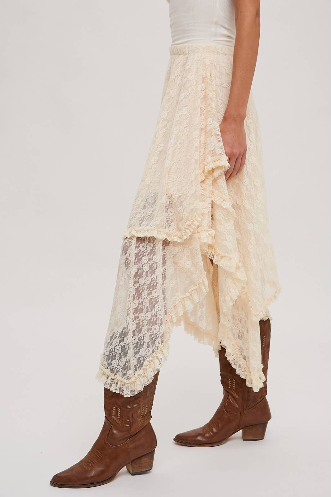 Person wearing a white lace skirt and brown boots on a white background