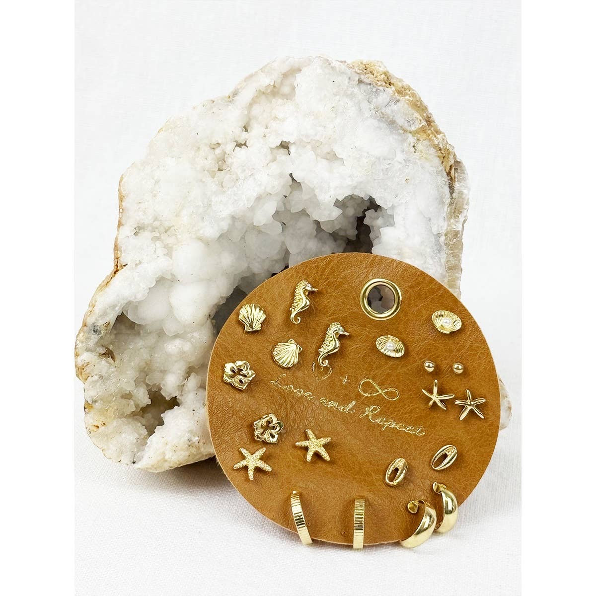 Set of gold earrings on a wooden display card with a white rock formation in the background