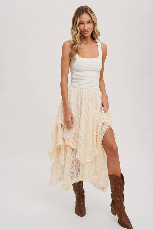 Woman wearing a white tank top and beige lace skirt with brown boots on a white background