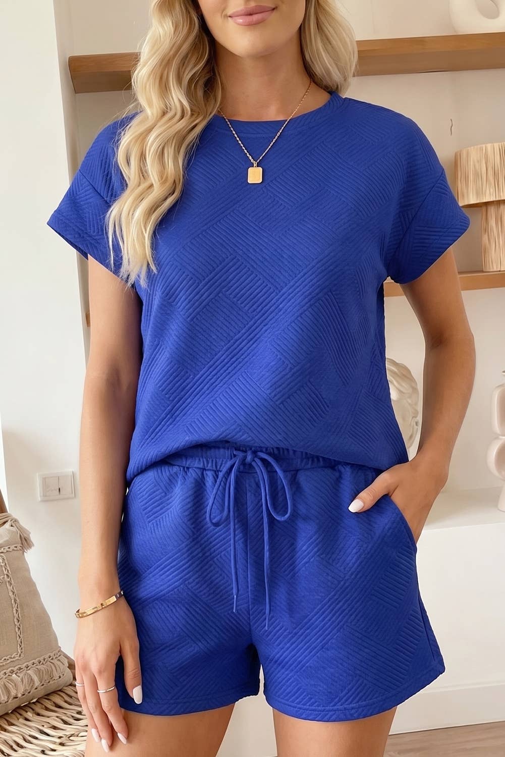 Woman wearing a blue textured outfit with shorts indoors.