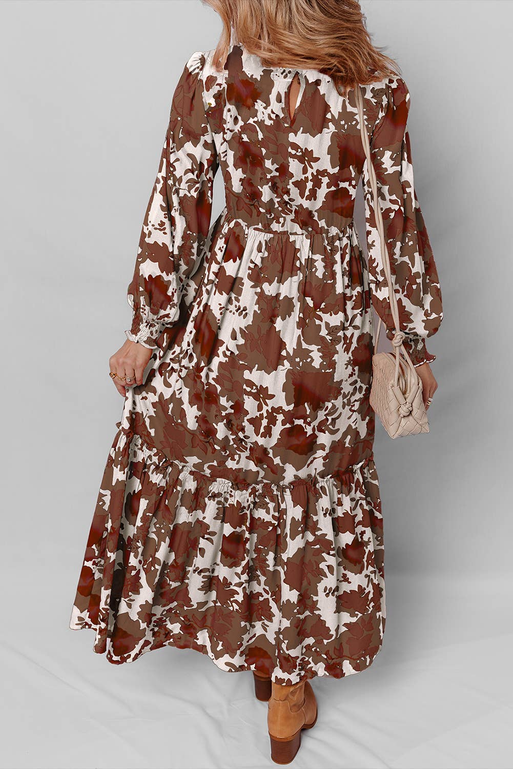 Woman wearing a long floral dress with brown and white pattern on a plain background