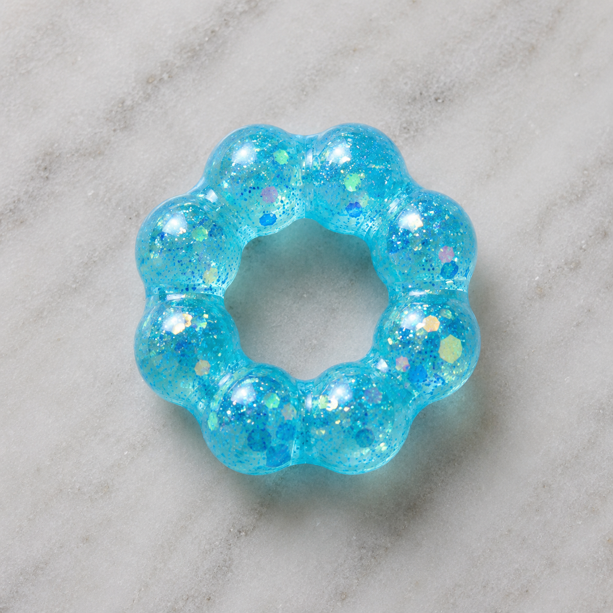 Blue glittery squishy bracelet on a marble surface.