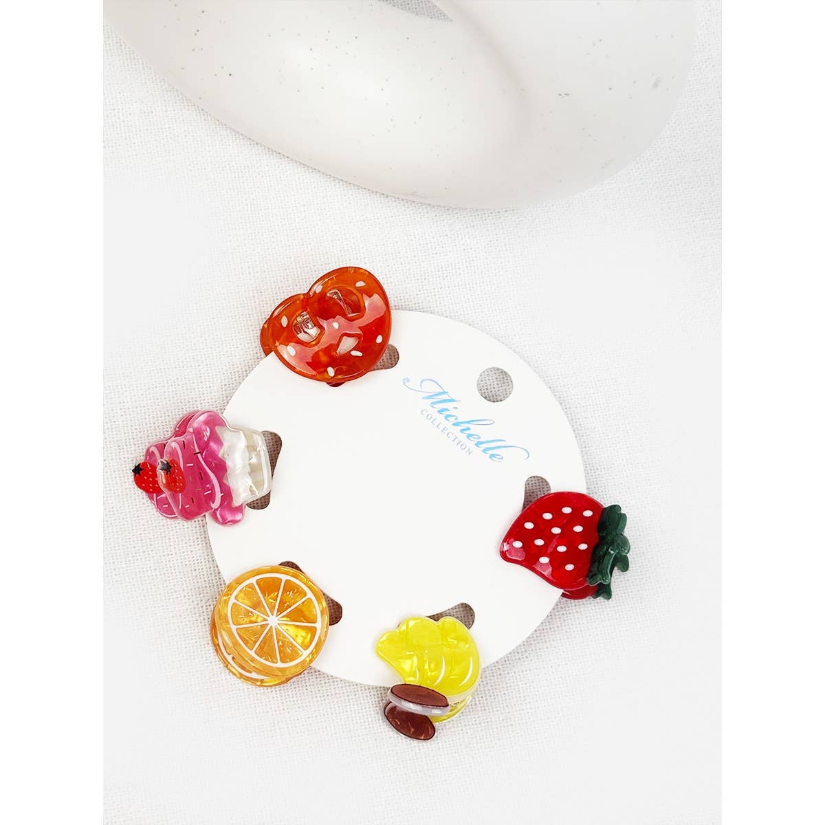 Set of colorful fruit-shaped hair clips on a white background