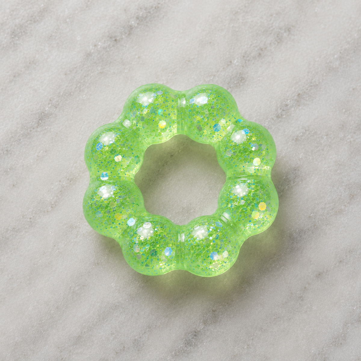 Green glittery squishy bracelet on a marble surface.