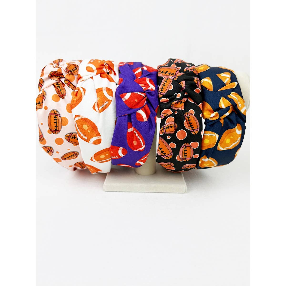 Four colorful headbands with football patterned designs on a white background