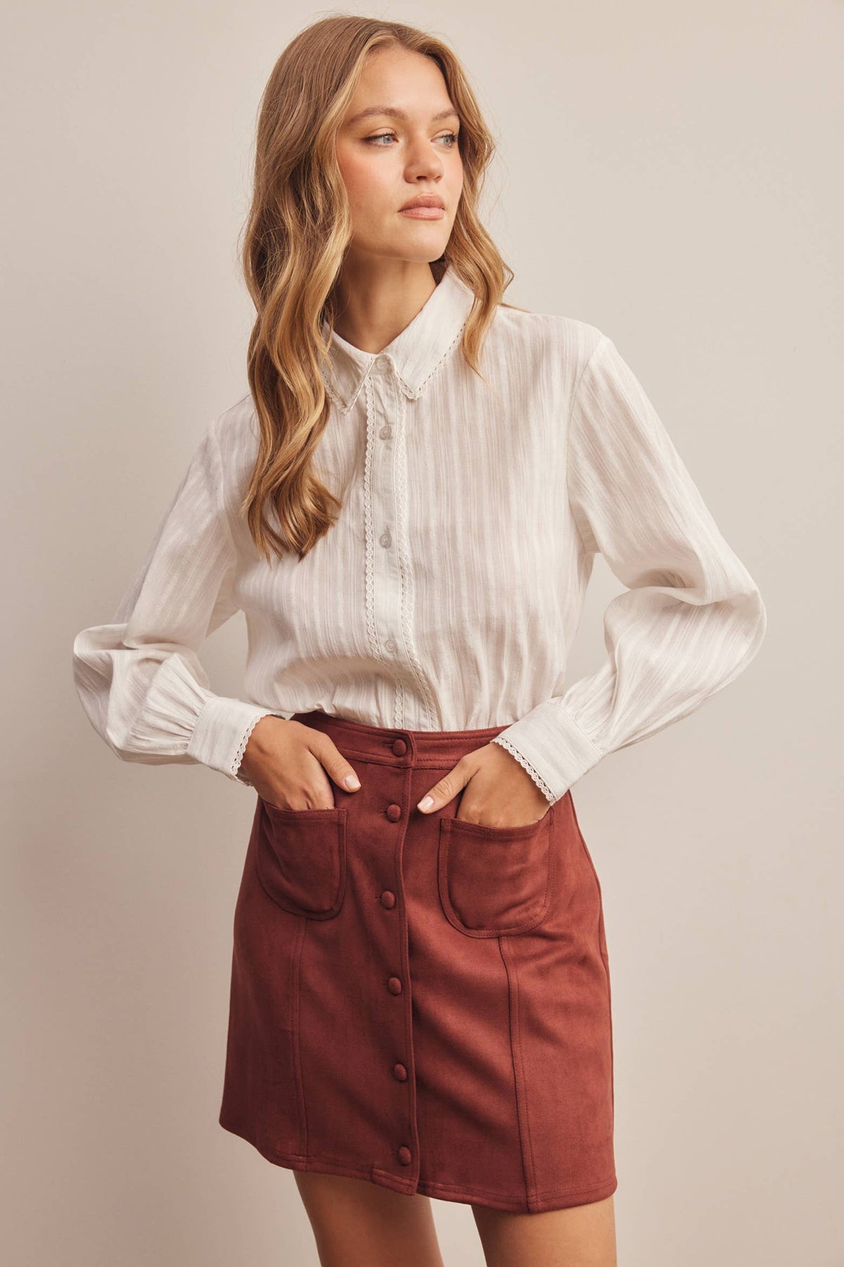 Woman wearing a white blouse and red skirt against a beige background