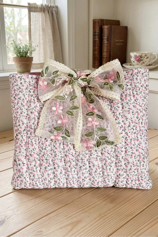 Floral-patterned bible cover with a decorative bow on a wooden floor