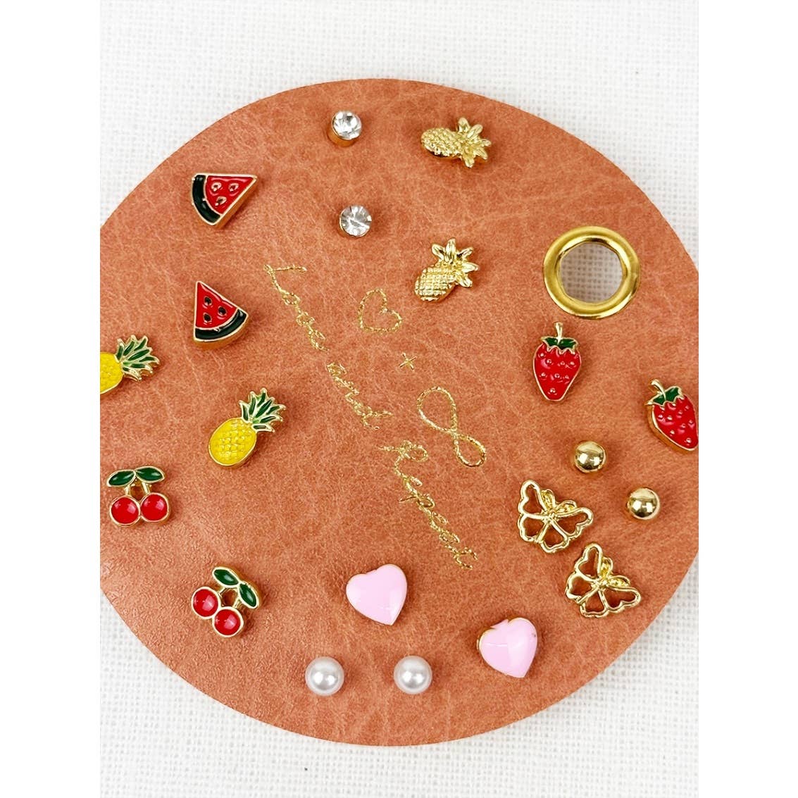 Collection of various earrings on a round brown card with decorative text.