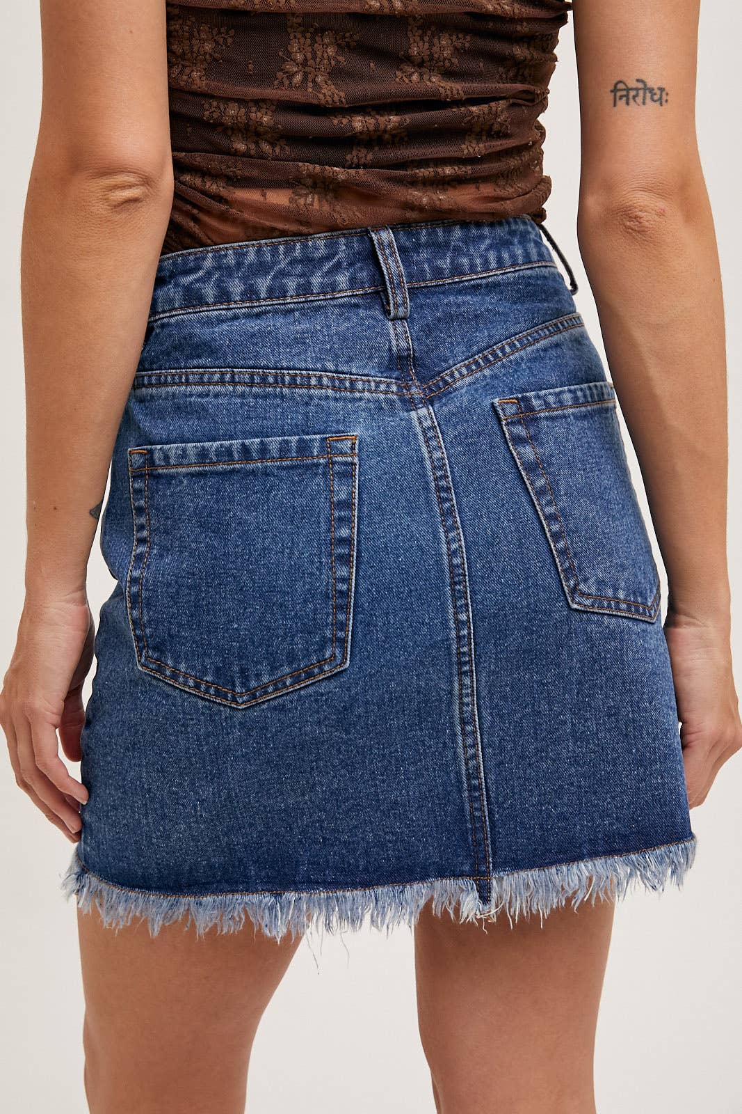 Person wearing a blue denim skirt with a plain background