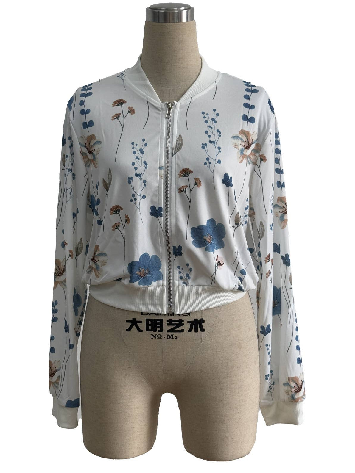 A long-sleeve zip-front jacket displayed on a beige mannequin torso against a white background, with Chinese text at the top and a watermark near the hem.
