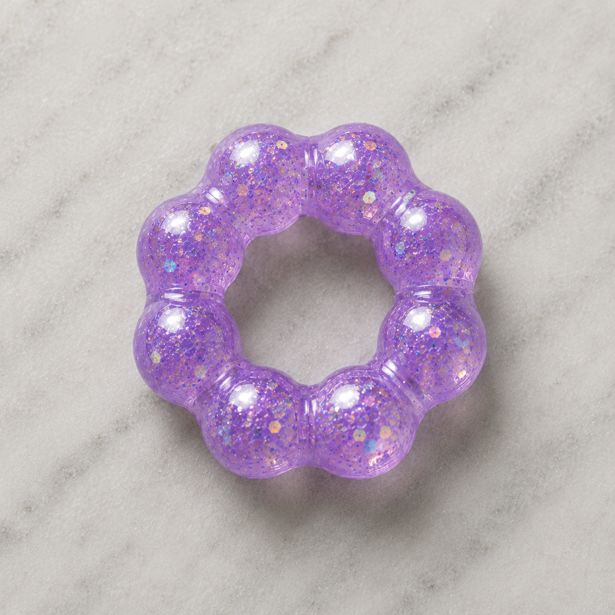 Purple glittery squishy bracelet on a marble surface.
